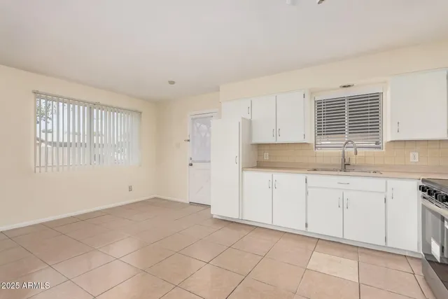 a kitchen with granite countertop white cabinets a sink a stove and a window