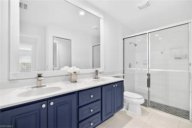 a bathroom with a double vanity sink toilet mirror and shower