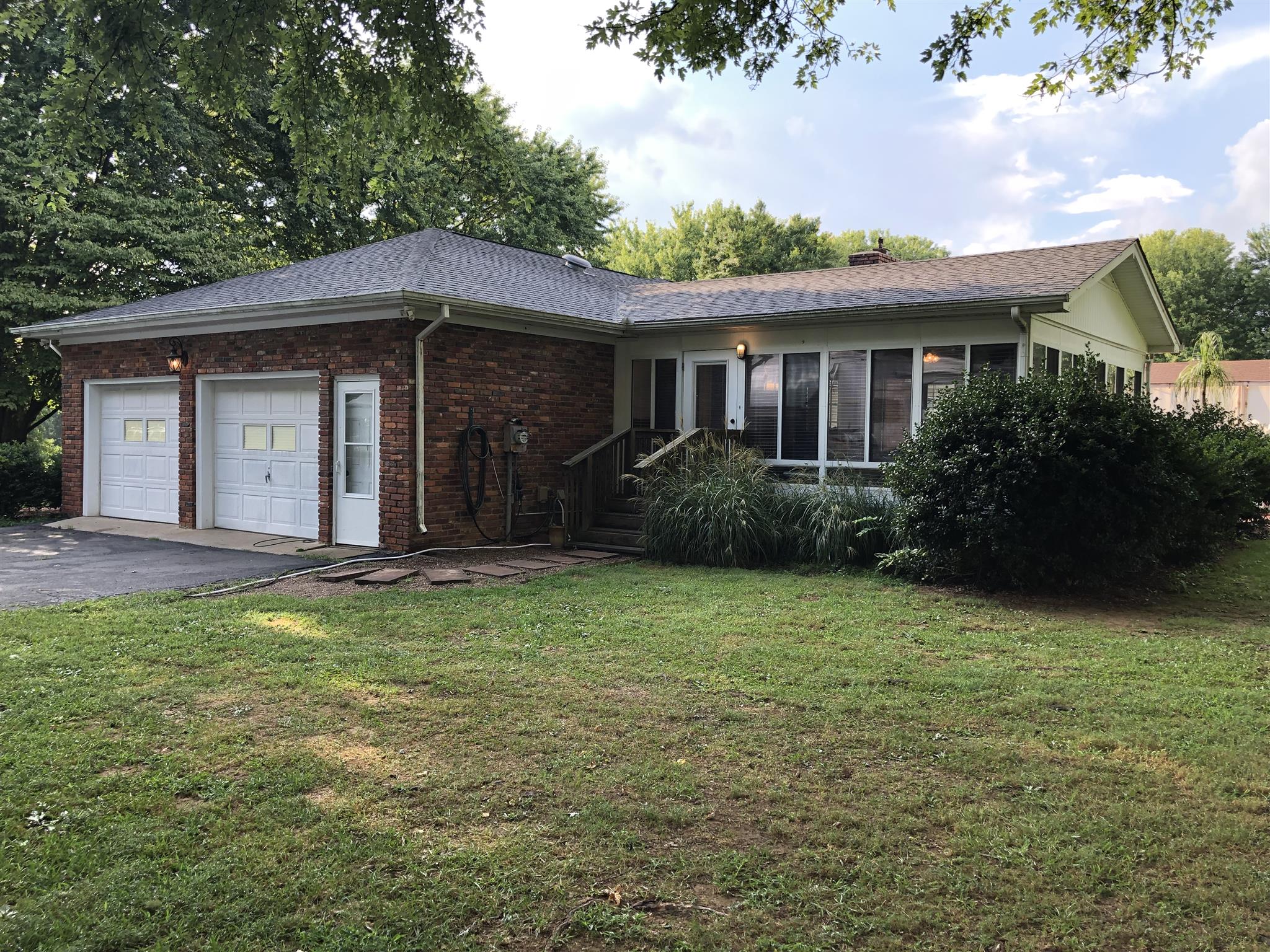 208 Riggs Avenue Portland, TN 37148 - Photo 18 of 26 Side view of the house showing 2 car garage with pedestrian door and entrance to sunroom.