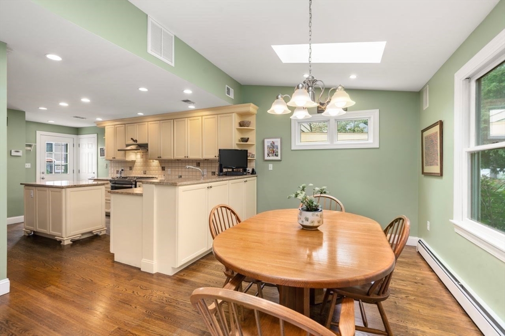 34 Palmer Road Newton, MA 02468 - Photo 17 of 26 a kitchen with kitchen island a white refrigerator a sink dishwasher a dining table and chairs with wooden floor