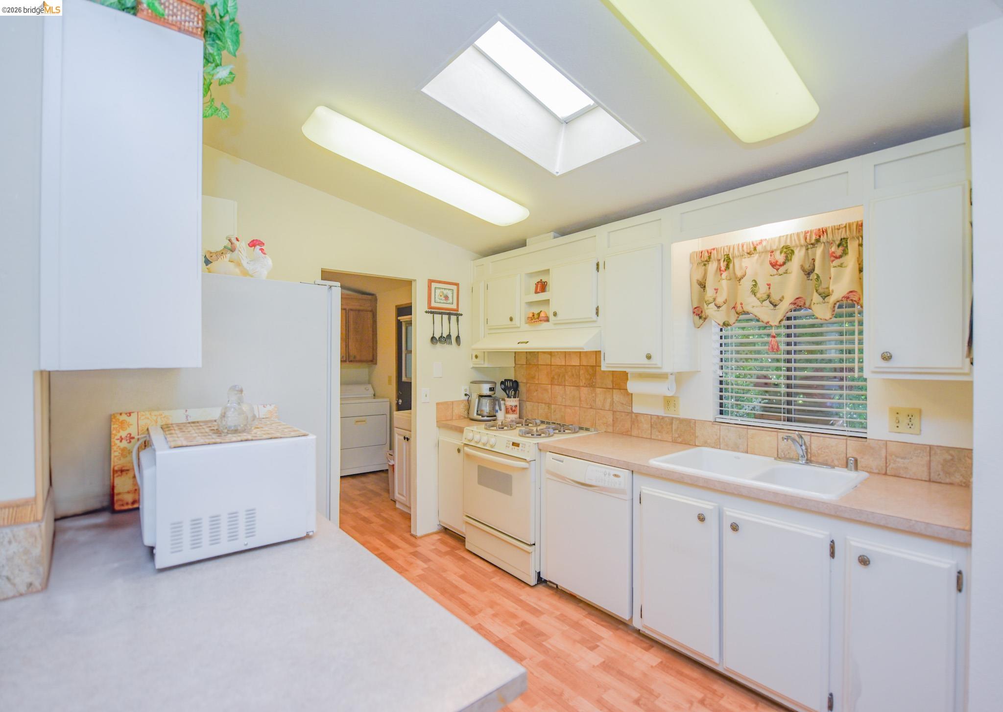 18717 Mill Villa Road, Unit 235 Jamestown, CA 95327 - Photo 11 of 26 Kitchen featuring white appliances, a skylight, light countertops, washer / clothes dryer, and vaulted ceiling