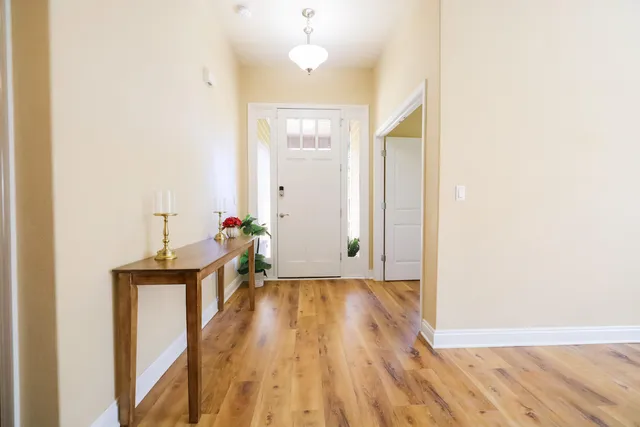 a view of a hallway with wooden floor and a bathroom