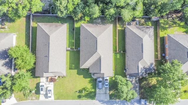 an aerial view of residential houses with outdoor space and trees