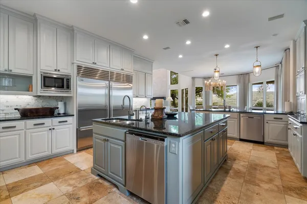 a kitchen with stainless steel appliances granite countertop a sink a stove and a refrigerator