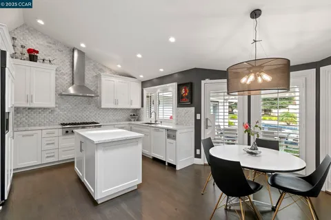 a kitchen with stainless steel appliances a dining table chairs and white cabinets