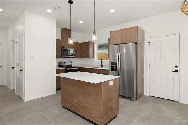 a kitchen with stainless steel appliances granite countertop a refrigerator a oven and a sink with wooden floor