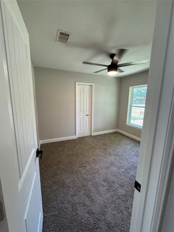 an empty room with windows and fan