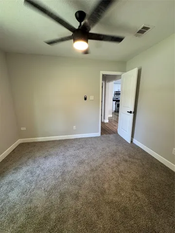 an empty room with a ceiling fan and a window