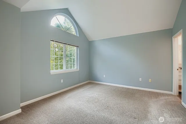 an empty room with a window and a chandelier fan
