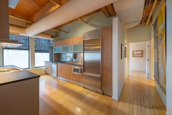 a kitchen with stainless steel appliances kitchen island granite countertop a refrigerator and a sink