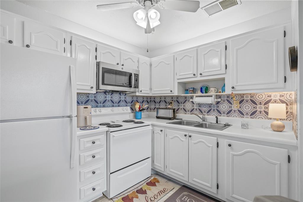 11923 Boynton Lane, Unit B New Port Richey, FL 34654 - Photo 12 of 34 a kitchen with white cabinets sink and stainless steel appliances