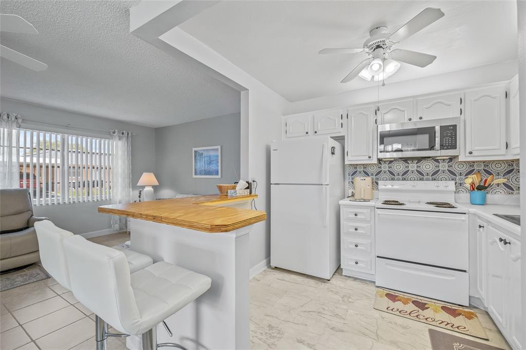 11923 Boynton Lane, Unit B New Port Richey, FL 34654 - Photo 10 of 34 a room with stainless steel appliances kitchen island granite countertop a sink a stove a dining table and chairs