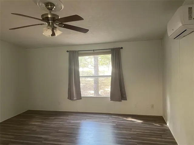 an empty room with wooden floor fan and windows