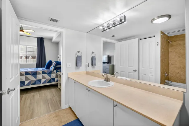 a en suite bathroom with a granite countertop sink and a large mirror