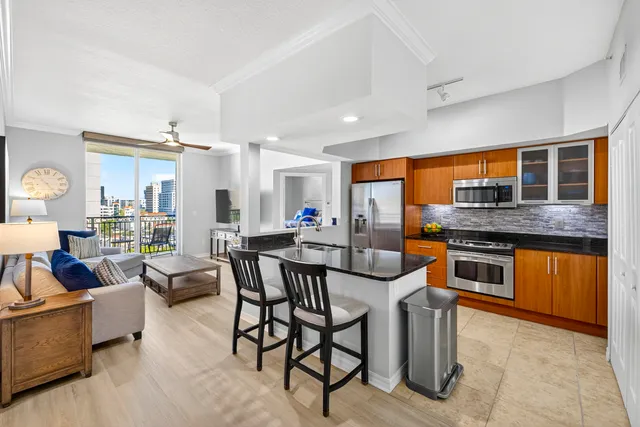 a kitchen with stainless steel appliances granite countertop a stove top oven a sink dishwasher a dining table and chairs with wooden floor