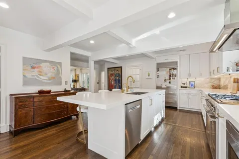 a large white kitchen with stainless steel appliances granite countertop a stove and a sink