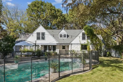 a view of a white house next to a yard with big trees