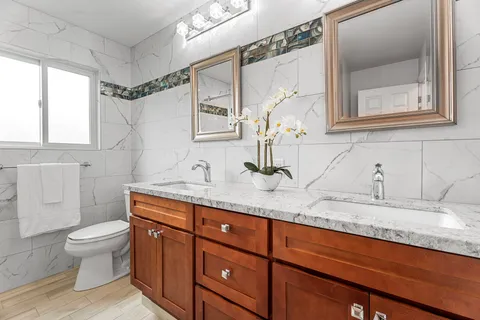 a bathroom with a granite countertop sink mirror vanity and toilet