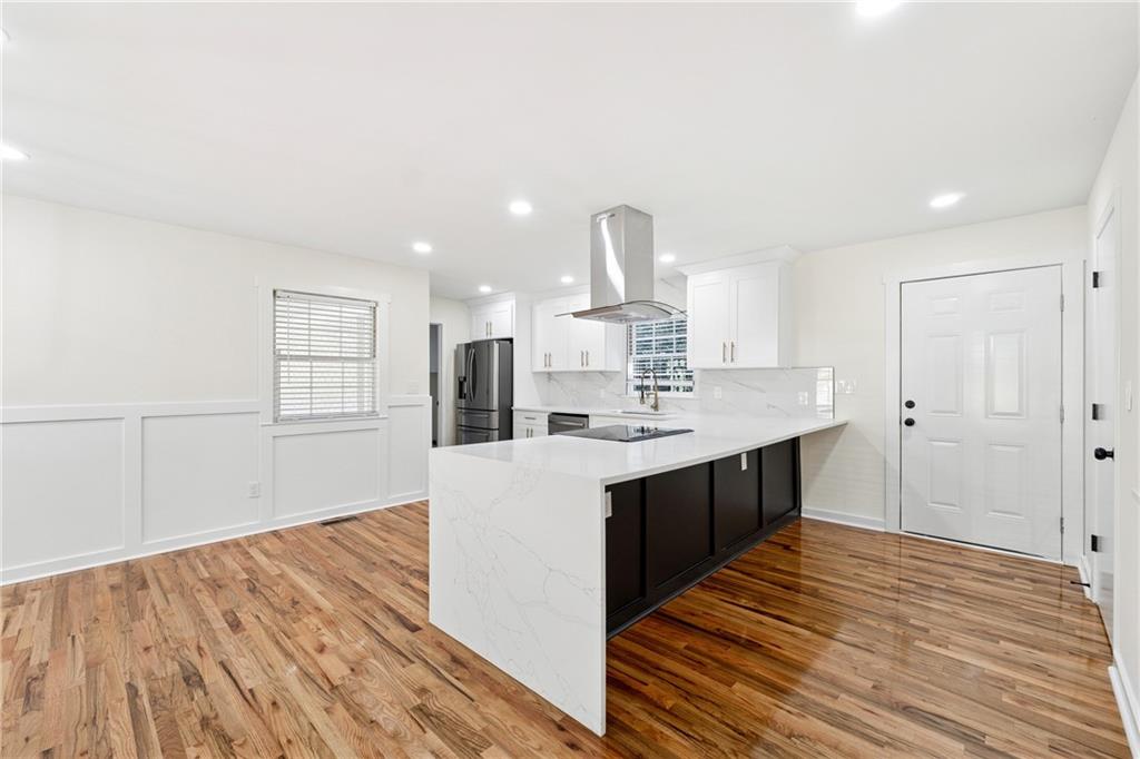 2055 Oak Road Southwest Snellville, GA 30078 - Photo 10 of 33 a large kitchen with kitchen island a sink dishwasher a stove and a refrigerator with wooden floor