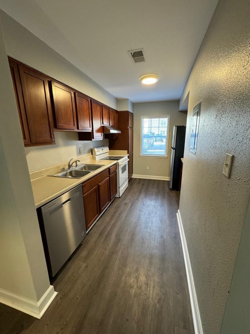 a kitchen with stainless steel appliances granite countertop a stove a sink dishwasher a refrigerator and wooden floor