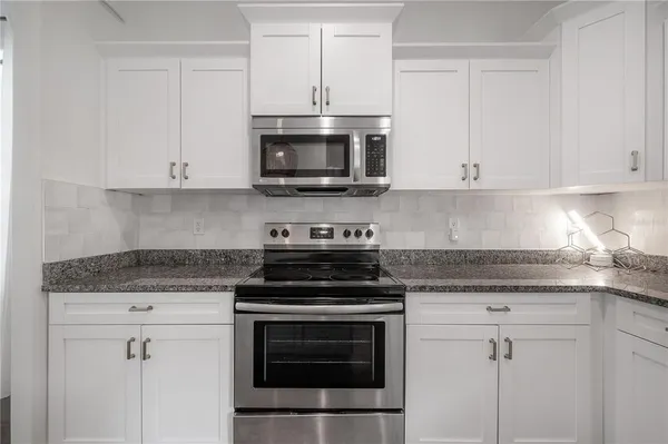 a kitchen with stainless steel appliances granite countertop grey cabinets a stove a sink and dishwasher