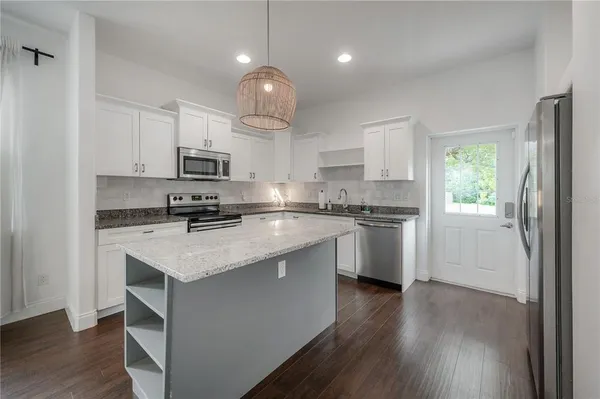 a kitchen with kitchen island granite countertop a sink cabinets and wooden floor