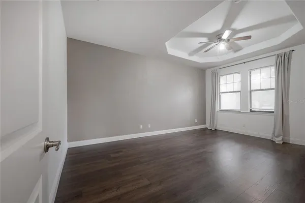 an empty room with wooden floor fan and windows