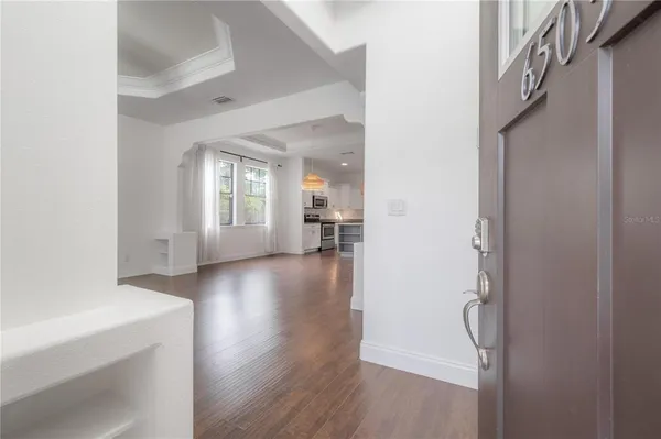 a view of a hallway view with wooden floor and a living room