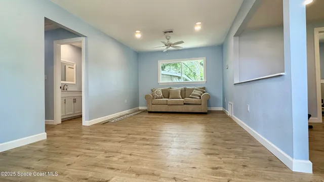 a view of an empty room with a window and kitchen view