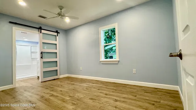a view of empty room with wooden floor and fan