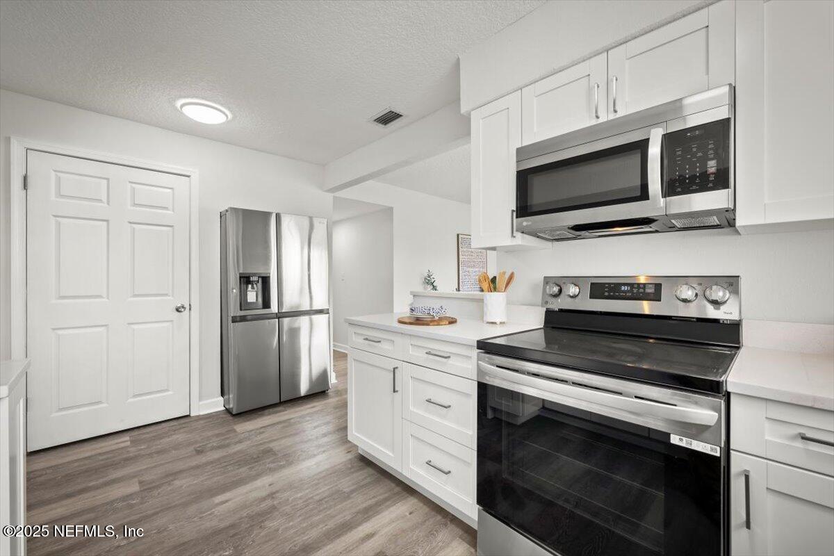 2905 Sandhurst Road East Jacksonville, FL 32277 - Photo 14 of 28 a kitchen with white cabinets and stainless steel appliances