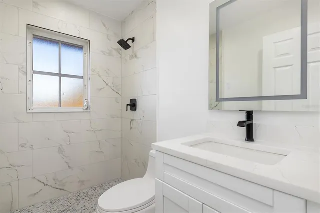 a bathroom with a granite countertop toilet sink and shower