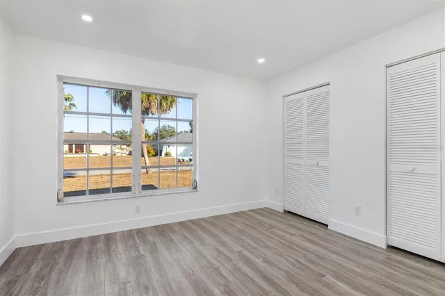 an empty room with wooden floor and windows