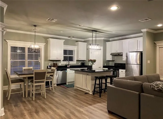 a kitchen with stainless steel appliances kitchen island granite countertop a table chairs and a refrigerator