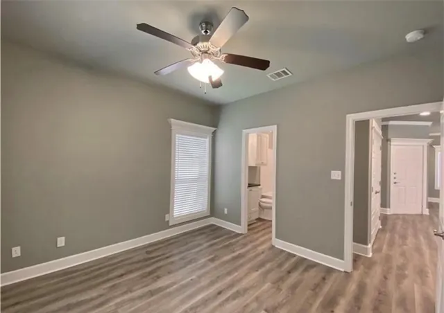 an empty room with wooden floor and ceiling fan