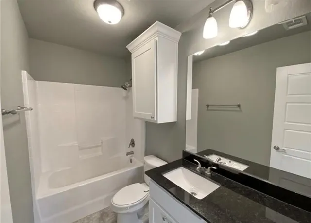 a bathroom with a granite countertop sink toilet a mirror and shower