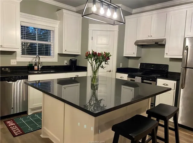 a kitchen with a counter space a sink a stove and cabinets