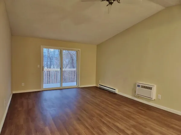 a view of an empty room with a window and wooden floor