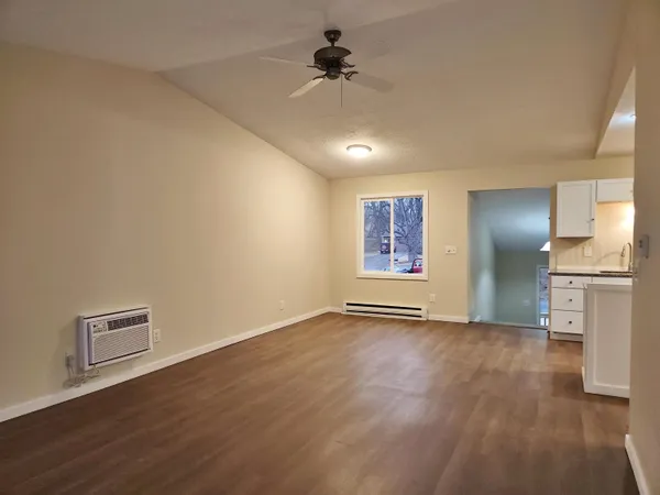 an empty room with wooden floor fan and windows