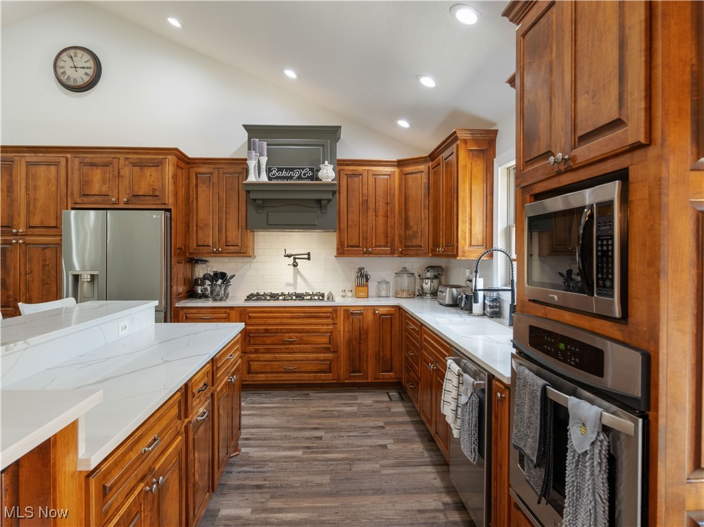 426 Bostic Road Gallipolis, OH 45631 - Photo 14 of 45 Kitchen with stainless steel appliances, lofted ceiling, backsplash, brown cabinets, and light stone counters