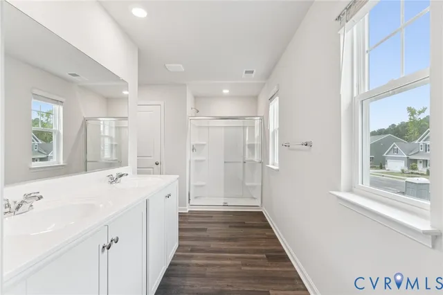 a spacious bathroom with a double vanity sink a large mirror and shower