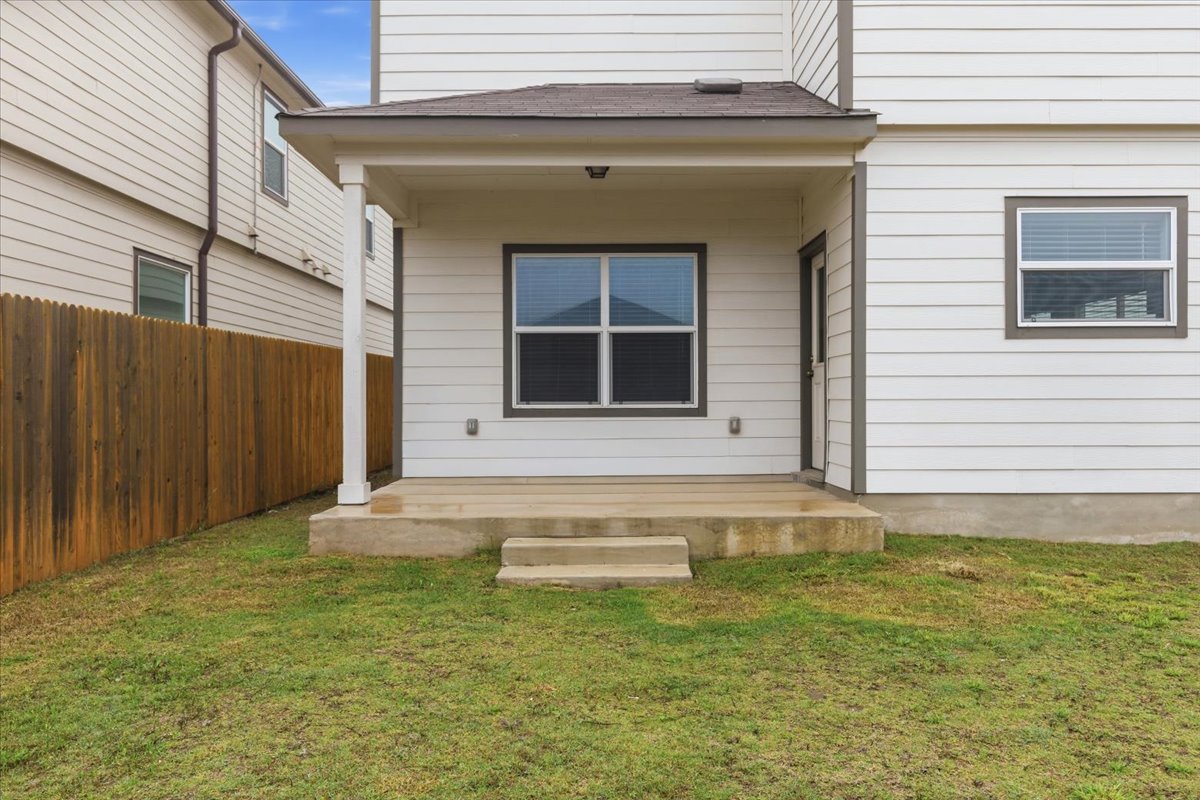 101 Rowdy Yates Way Jarrell, TX 76537 - Photo 29 of 32 Rear patio featuring a concrete slab with two steps, covered by an awning with a recessed light fixture