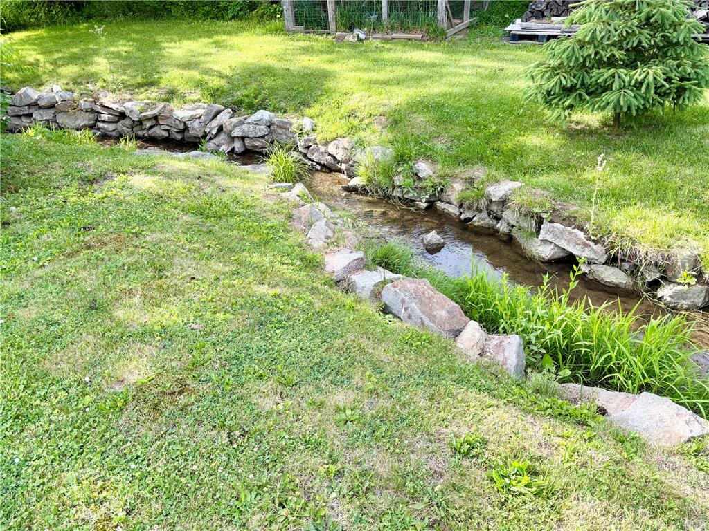 7241 Decatur Street New Tripoli, PA 18066 - Photo 35 of 36 A tranquil creek winds through a lush, green yard, offering natural beauty and serene sounds.