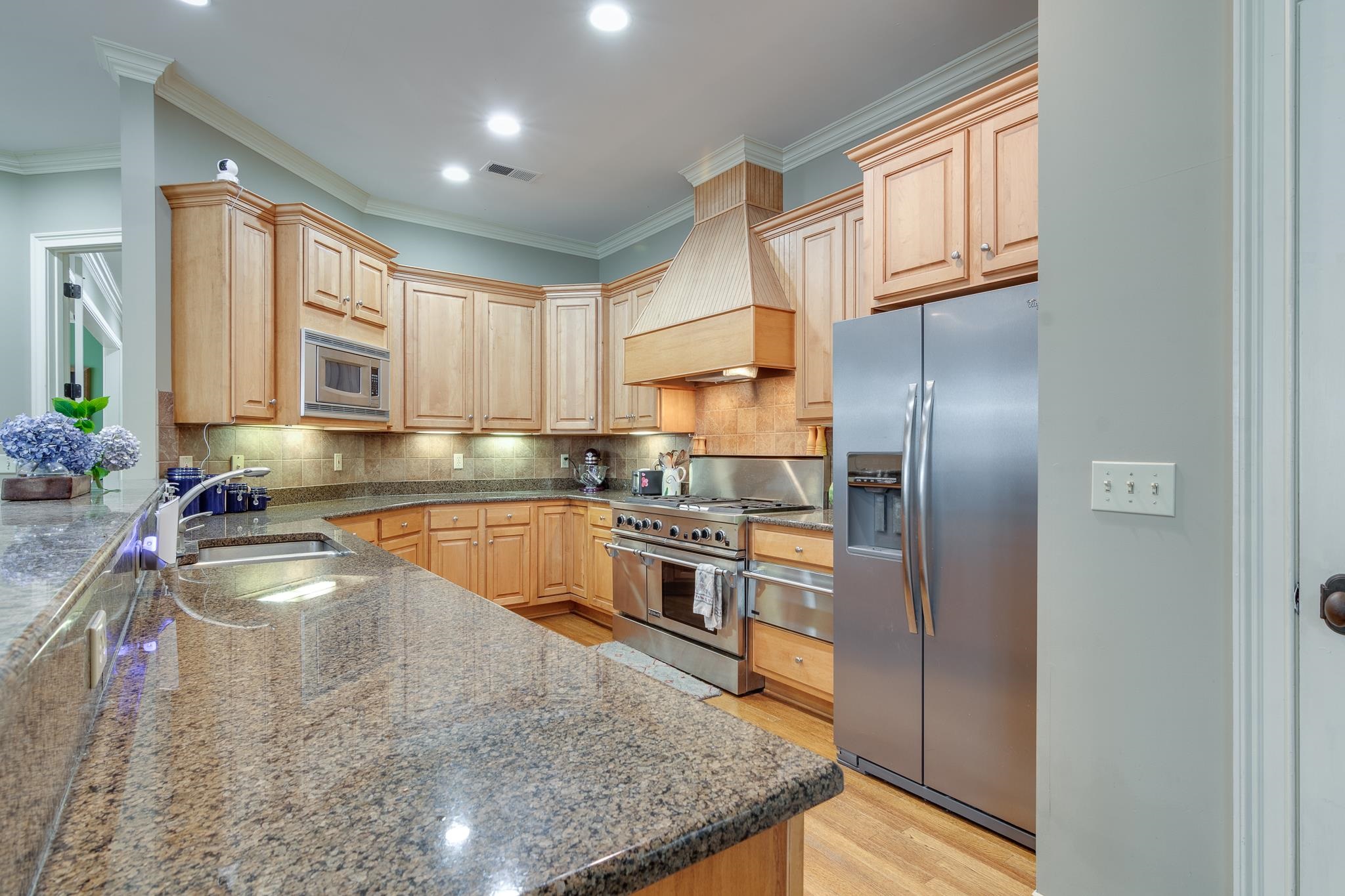 226 North White Station Road Memphis, TN 38117 - Photo 13 of 31 Kitchen with custom range hood, light hardwood / wood-style flooring, appliances with stainless steel finishes, sink, and tasteful backsplash