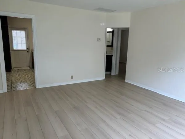 a view of an empty room with wooden floor and a window