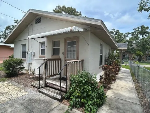 a view of a house with a small yard plants and large tree