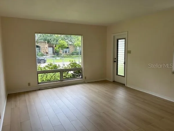 a view of an empty room with wooden floor and a window