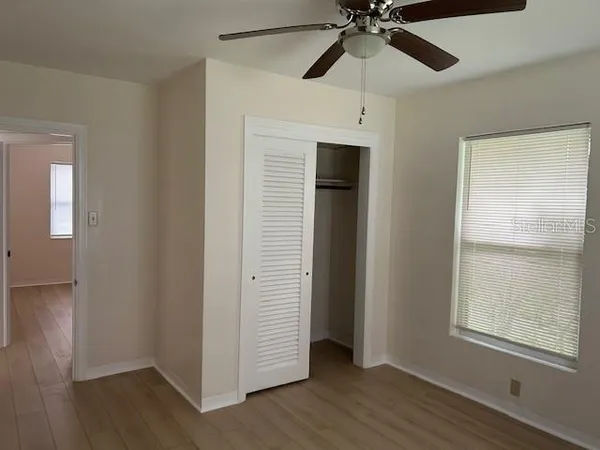 an empty room with wooden floor closet and chandelier fan