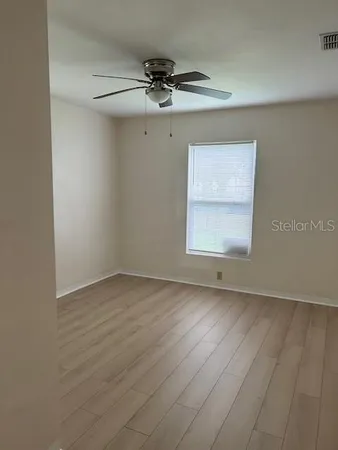 an empty room with a window and a fan