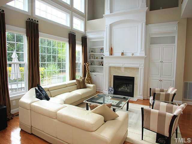 Hardwooded living room with grand fireplace, high windowns with lots of natural light, built-in shelves, cabinets, lighting, and easy access to kitchen, foyer, and master bedroom. Den/Family/Great Room